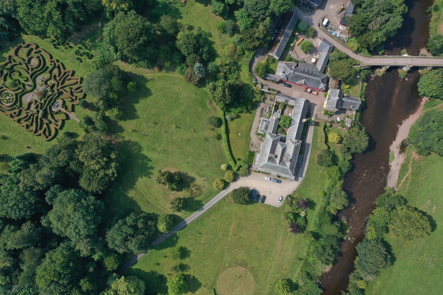 An aerial view of Penpont’s house, gardens and hedge maze beside the River Usk.