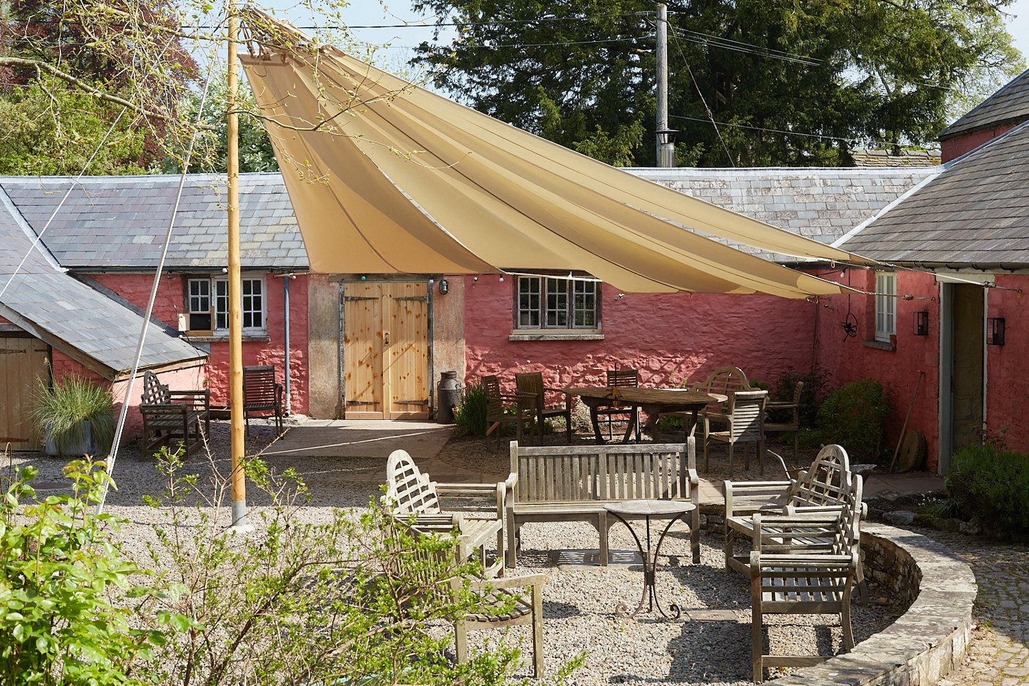 Tables and chairs beneath a sail canopy in Penpont’s sunny courtyard.